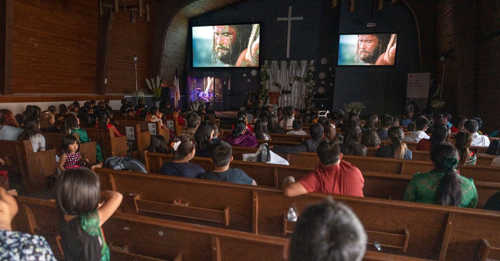 Church pews filled with people watching the Jesus Film